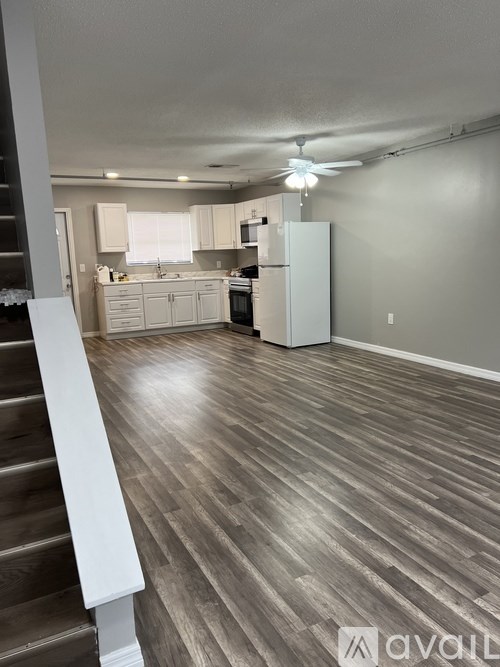 A spacious kitchen with wood flooring and a staircase on the left.