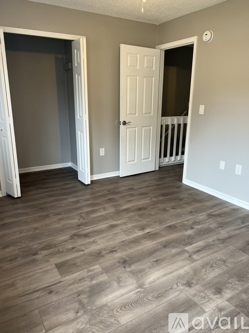 A room with a white door and a wooden floor.