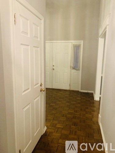 A hallway with a wooden floor and white doors.