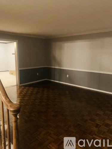A room with wooden flooring and a staircase on the left side.