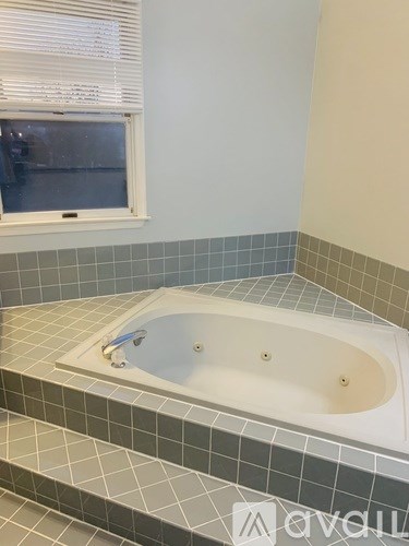 A white bathtub with a grey tile floor and wall.