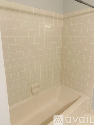 A white tiled bathroom with a white bathtub.