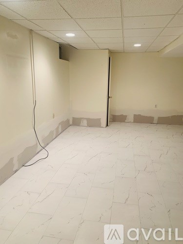 A room with a white tile floor and a white wall with a cable running along it.