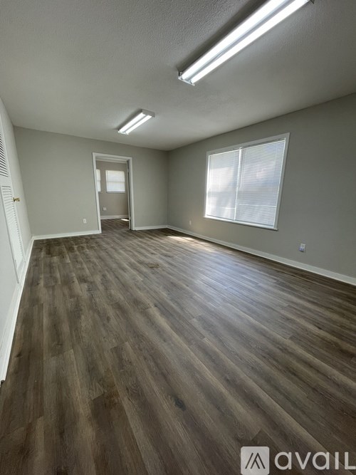 A room with wooden flooring and a window with blinds.