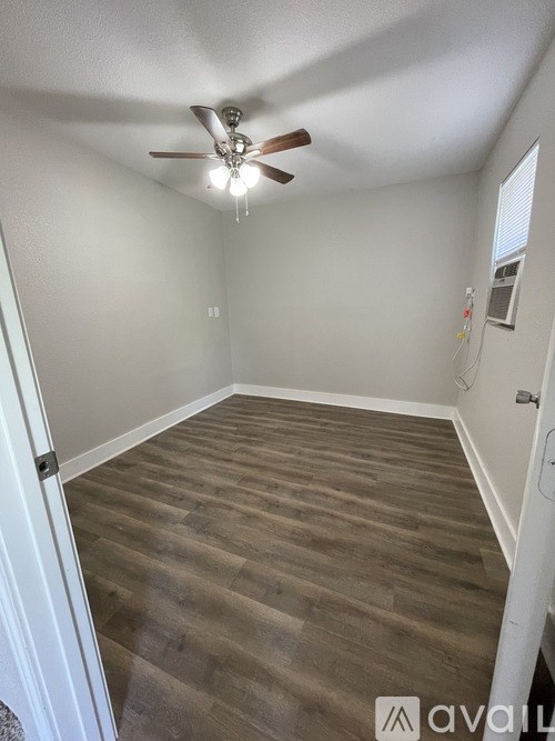 A room with a ceiling fan and wooden flooring.