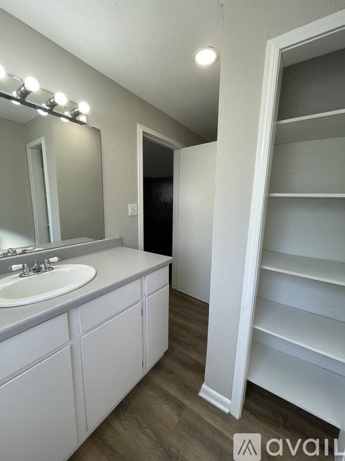 A bathroom with a sink, mirror, and shelves.