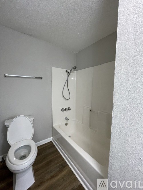 A white toilet is in a small bathroom with a walk-in shower.