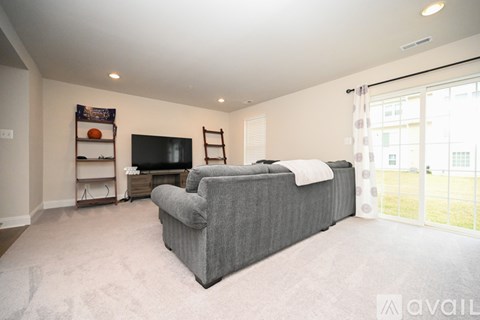 A living room with a grey couch and a television on a stand.