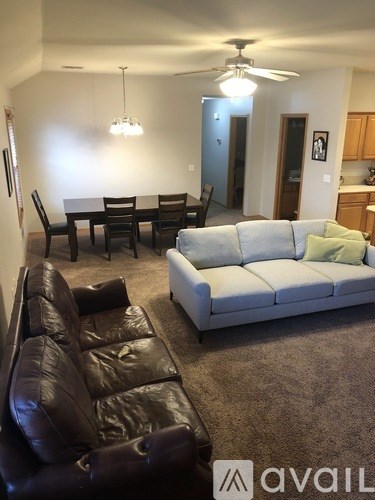A living room with a brown leather couch and a white couch.