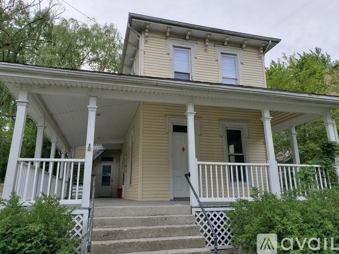 A yellow house with a porch and stairs leading to the front door.