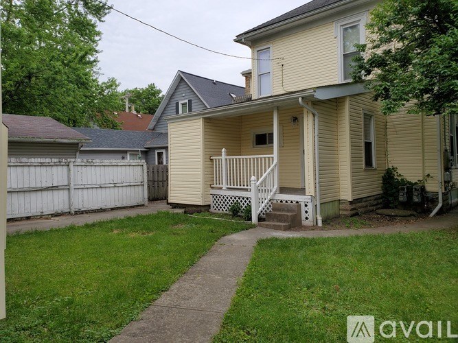 A house with a yellow siding and a white porch.