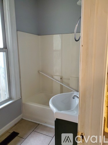 A white bathtub with a shower head is in a bathroom.