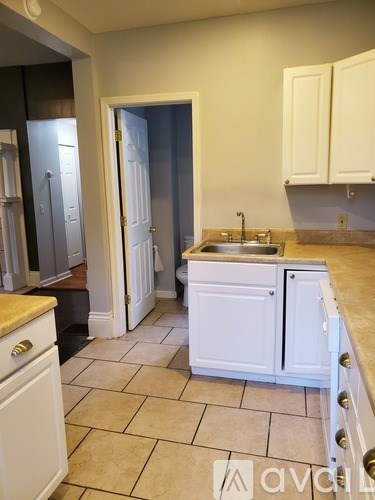 A kitchen with white cabinets and a tiled floor.