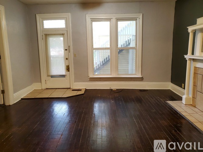 A room with a wooden floor and two doors leading to a balcony.