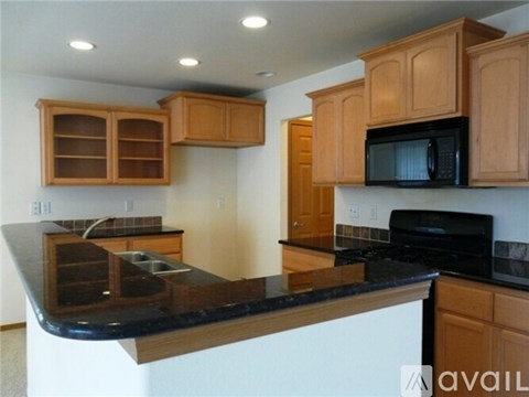 A kitchen with wooden cabinets and black countertops.