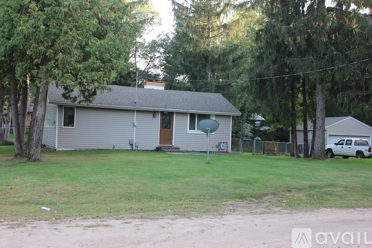 A house with a grey roof and a brown door is surrounded by trees.