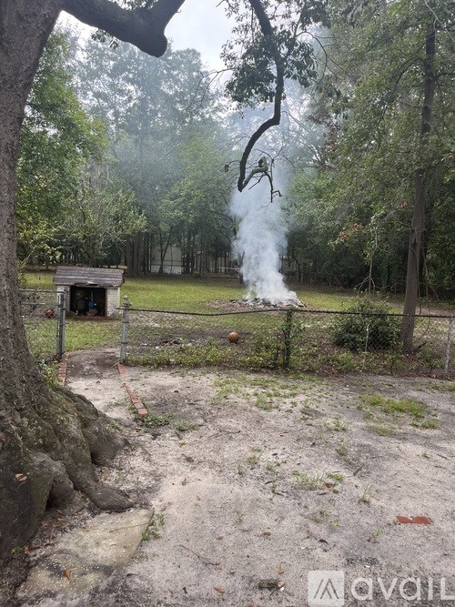 A small wooden structure is surrounded by a fence in a wooded area.