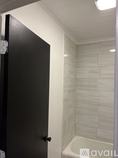 A black door is open to a white tiled bathroom.