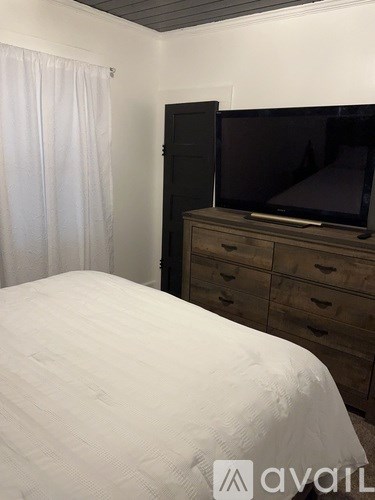 A bedroom with a bed, dresser, and a television.