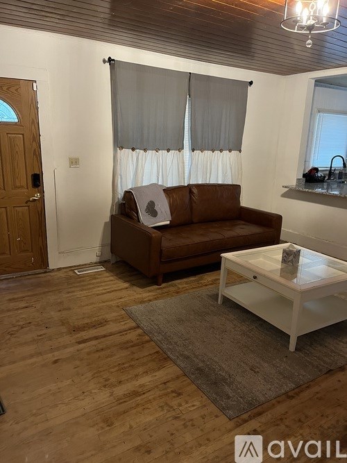 A brown couch sits in a room with wooden floors and a white coffee table.