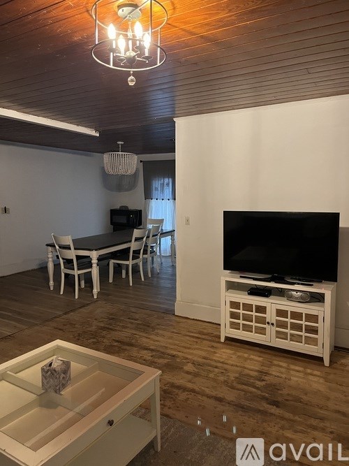 A living room with a television, a coffee table, and a chandelier.