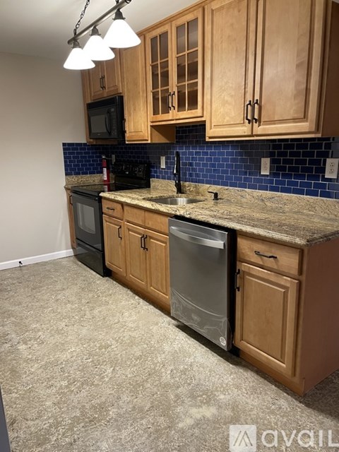 A kitchen with wooden cabinets and a black dishwasher.