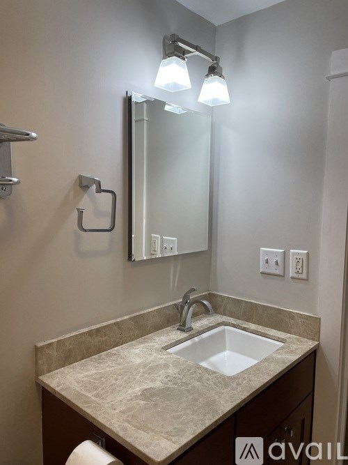 A bathroom with a sink, mirror, and light fixture.