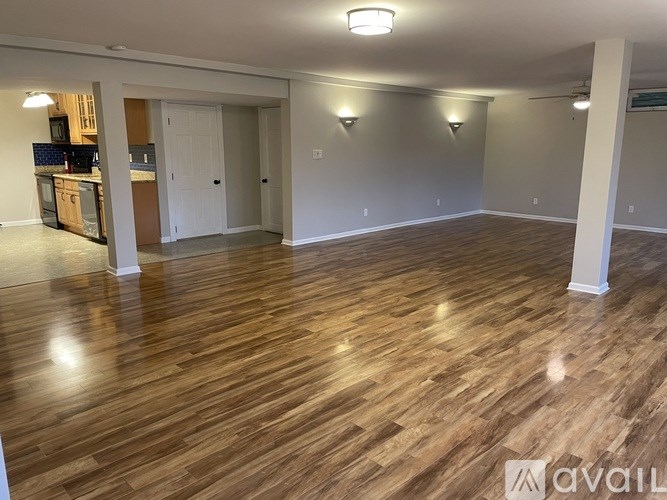 A spacious room with wooden flooring and white walls.