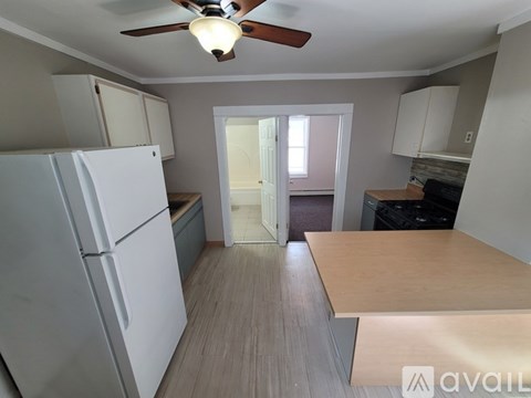 A kitchen with a white refrigerator and a ceiling fan.