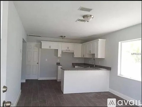 A kitchen with white cabinets and a black countertop is available for rent.