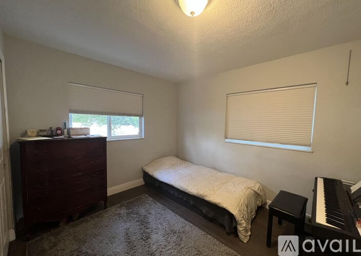 A bedroom with a bed, dresser, and a piano.