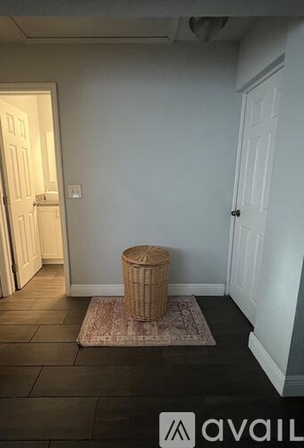 A room with a white door and a brown ottoman.