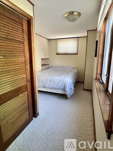 A bedroom with a bed, a window with blinds, and a wooden door.