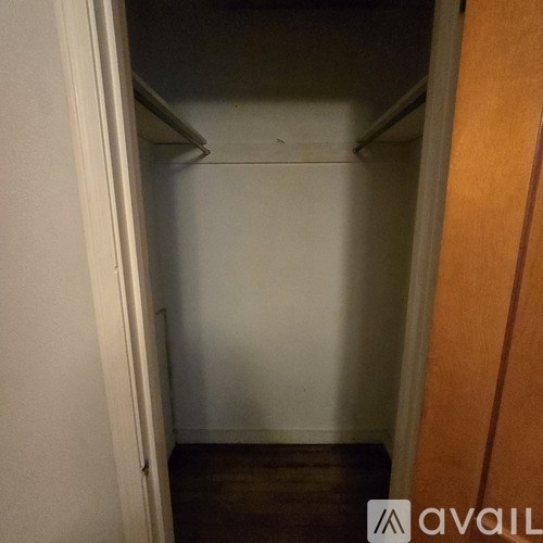 A small, empty closet with a wooden door on the right.