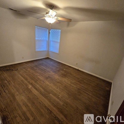 A room with wooden flooring and a ceiling fan.