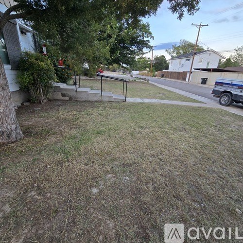A grassy area with a tree and a house in the background.