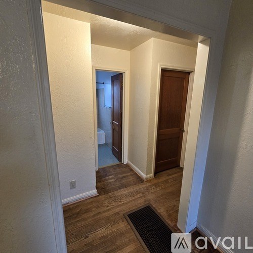 A hallway with a wooden door and a light switch on the wall.