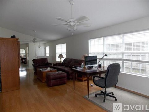 A living room with a brown leather couch and a black office chair.