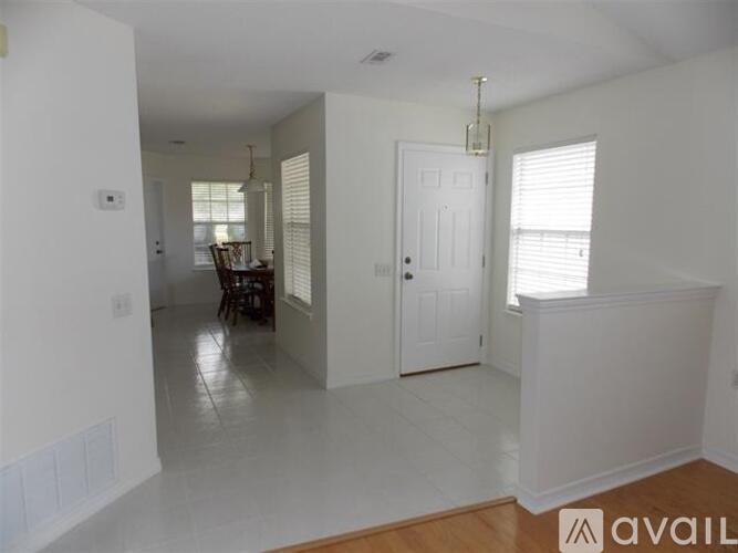 A room with a white door and a table with chairs in the background.