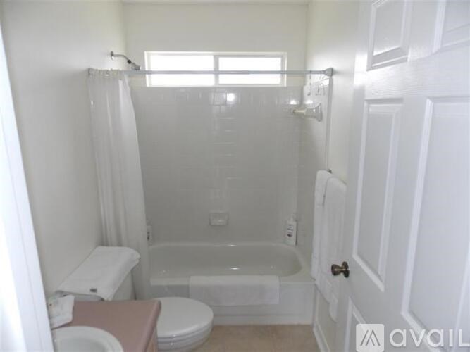 A white bathroom with a toilet, tub, and sink.