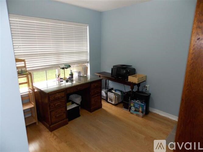 A room with a desk and a window with blinds.