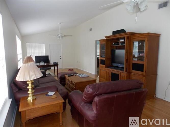 A living room with a red couch, a wooden coffee table, a lamp, a television, and a wooden cabinet.