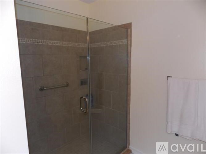 A shower stall with a glass door and a white towel hanging on the wall.