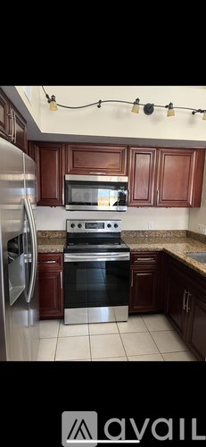 A kitchen with brown cabinets and a stainless steel refrigerator.