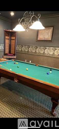 A pool table with a green felt top is in the foreground of the image.