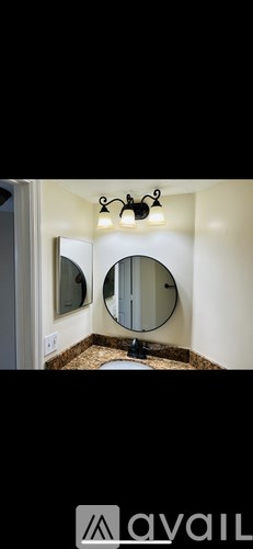 A bathroom with a round mirror and a light fixture above it.