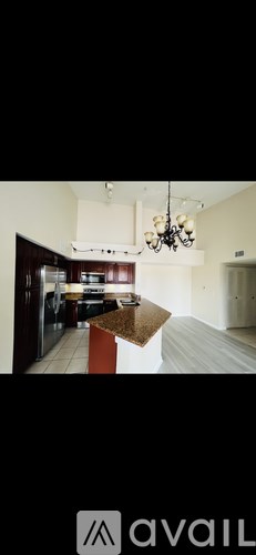 A modern kitchen with a granite countertop and a chandelier.