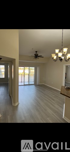 A spacious room with a ceiling fan and a chandelier.