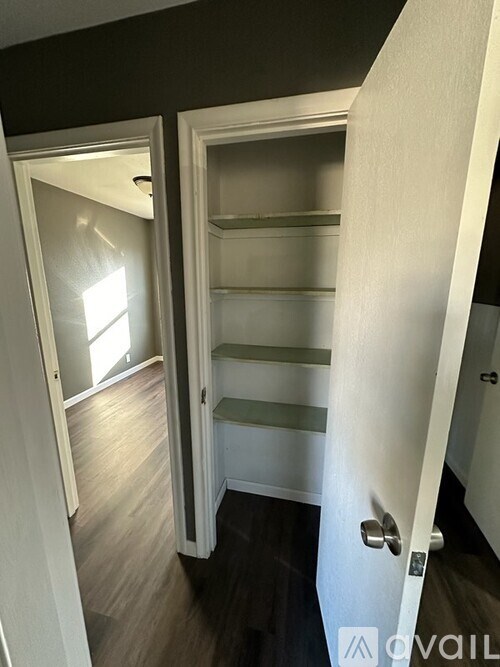 A white door is open to a room with a shelf.