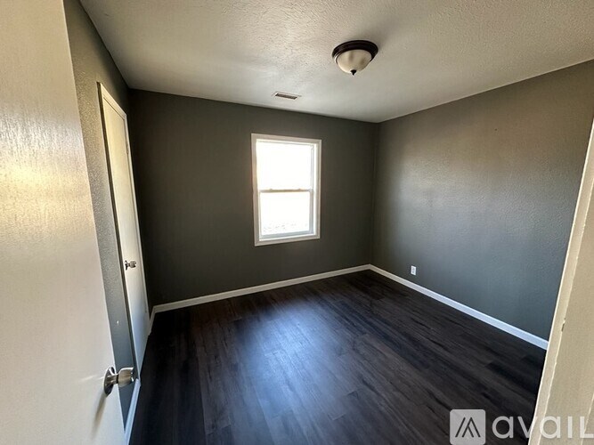 A room with a window and wooden flooring.